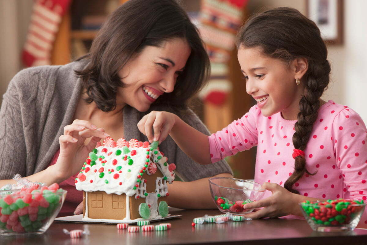 Mother and Daughter Decorating Gingerbread House Together for the Holidays