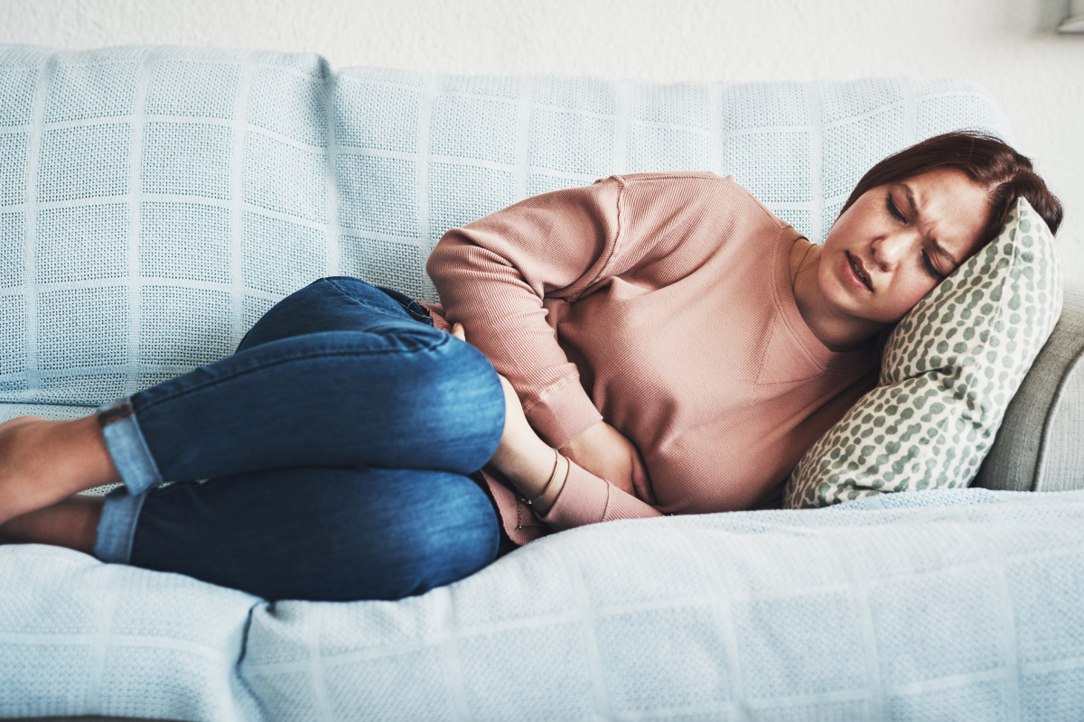 Woman on the couch suffering from heart disease symptoms including fatigue and nausea