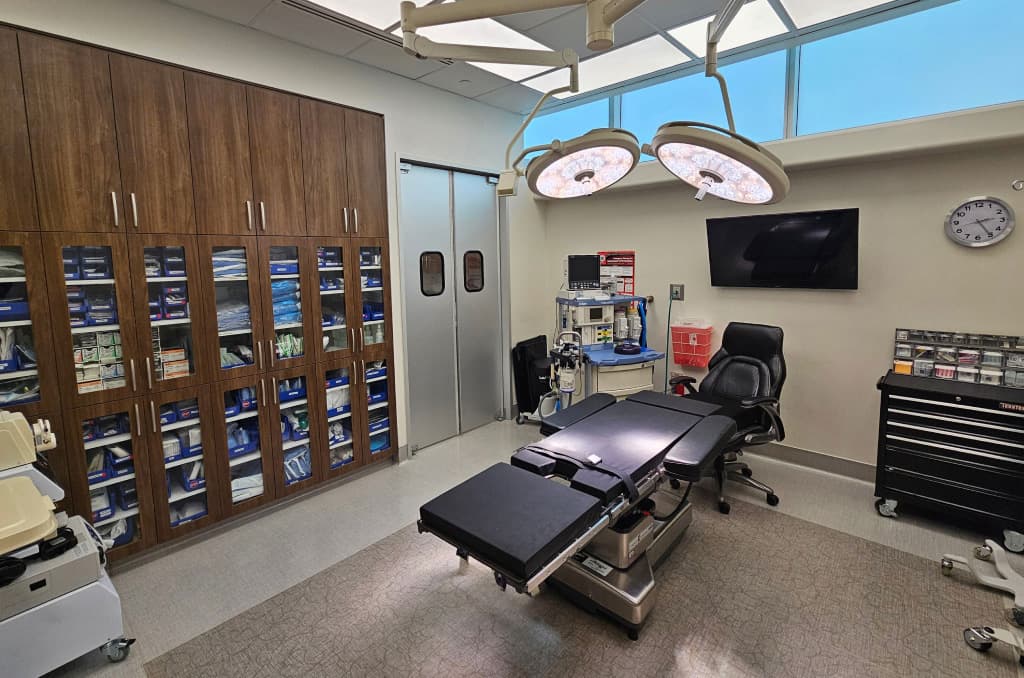 Operating room with bright LED overhead lights, fully equipped and Quad A certified to facilitate safe cosmetic surgery.