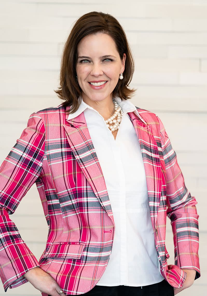 Portrait of Board Certified Plastic Surgeon Emily J. Kirby, MD smiling wearing a plaid pink blazer