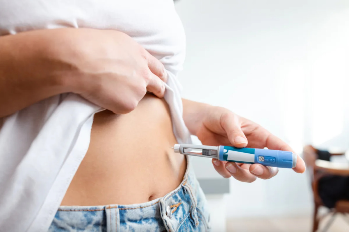 Woman administering GLP-1 weight loss injection in the abdomen