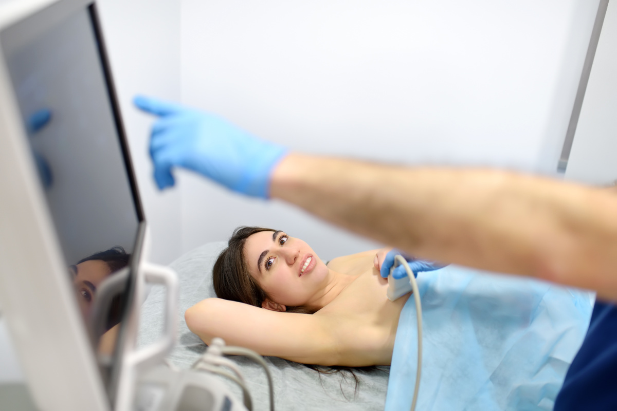 Young woman asking questions during an ultrasound for breast implant rupture detection