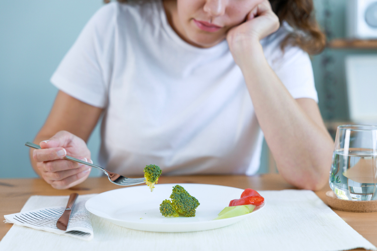 Faceless woman eating a plate of vegetables on a low calorie diet