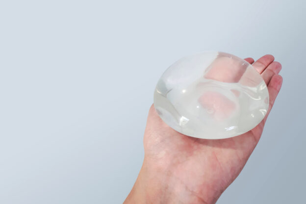 Hand holding a silicone breast implant