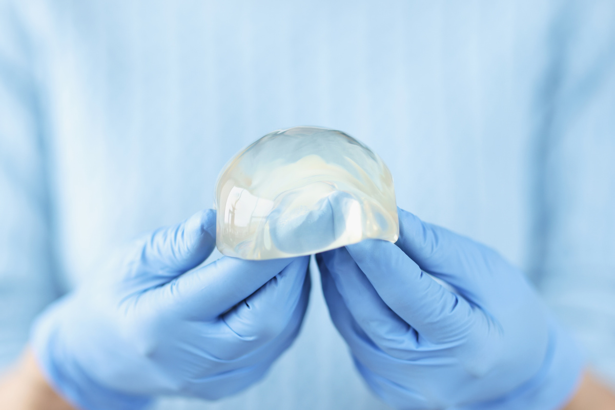 Close up of gloved hands holding a silicone breast implant