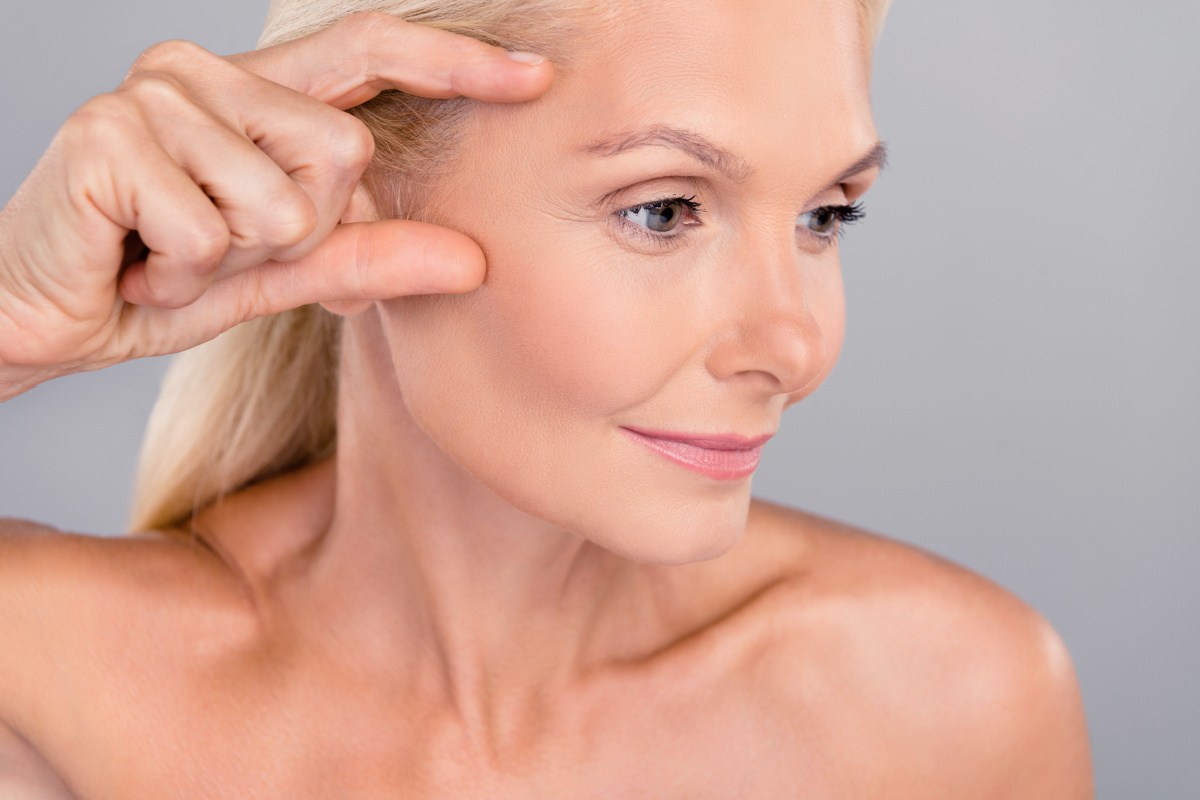 Mature woman lifting eyes and brow touching forehead